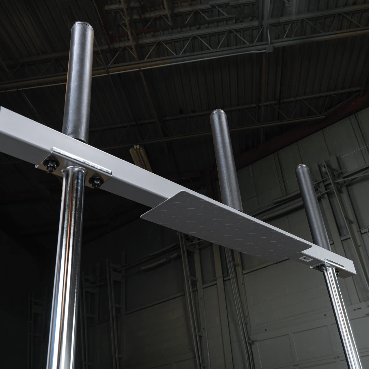 A close-up view of a sturdy metal training apparatus with two vertical poles and a horizontal platform, set against a dark industrial background.