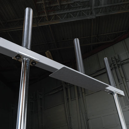 A close-up view of a sturdy metal training apparatus with two vertical poles and a horizontal platform, set against a dark industrial background.
