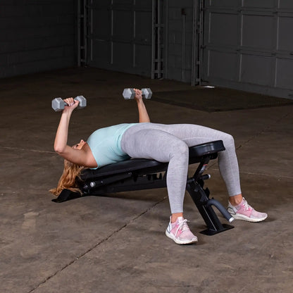 A woman performs a chest press exercise using dumbbells on the Body-Solid Pro ClubLine Adjustable Bench SFID325 in a gym setting.