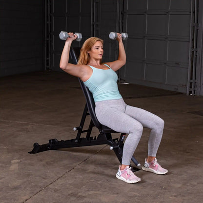 A woman performing an overhead dumbbell press on the Body-Solid Pro ClubLine Adjustable Bench SFID325 in a gym setting.