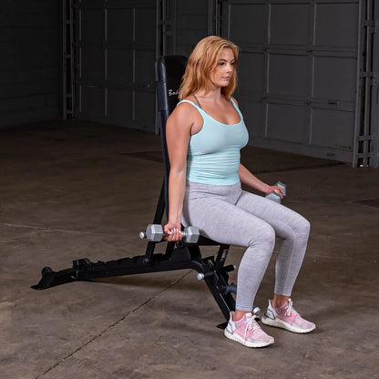 A woman performing a seated exercise with dumbbells on the Body-Solid Pro ClubLine Adjustable Bench SFID325 in a gym setting.