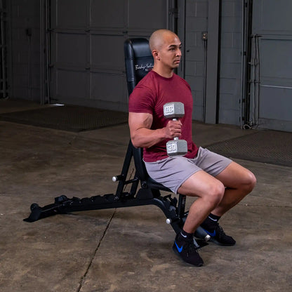 A person sitting on the Body-Solid Pro ClubLine Adjustable Bench SFID325, holding a dumbbell in one hand while preparing for a workout in a gym setting.