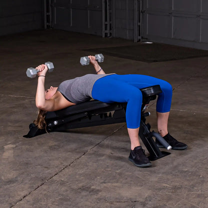 A woman performing a bench press exercise with dumbbells on the Body-Solid Pro ClubLine Adjustable Bench SFID325 in a gym setting.