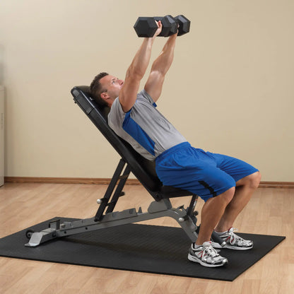 A person performing an overhead dumbbell press on the Body-Solid Pro ClubLine Adjustable Bench SFID325 in a home gym setting.