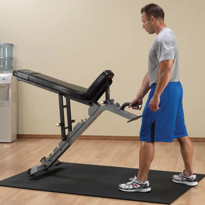 A person adjusting the Body-Solid Pro ClubLine Adjustable Bench SFID325 in a gym setting, standing on a black mat with a water cooler in the background.