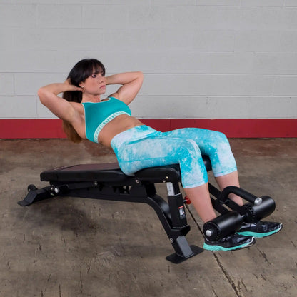 A woman in athletic wear performs a crunch on the Body-Solid Pro ClubLine Adjustable Bench SFID425 in a gym setting.