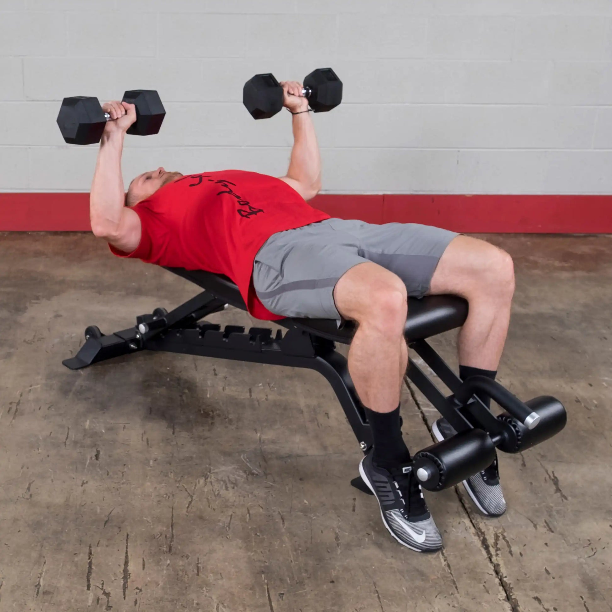 A person performing a dumbbell bench press on the Body-Solid Pro ClubLine Adjustable Bench SFID425, showcasing proper form and technique in a gym setting.