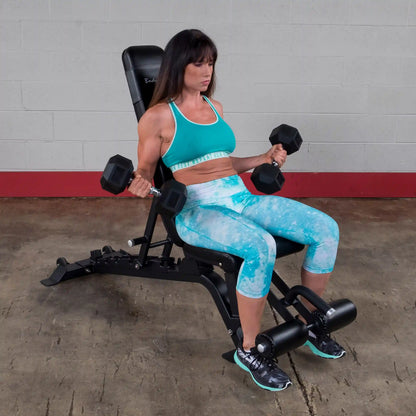 A woman performing a bicep curl exercise using dumbbells while seated on the Body-Solid Pro ClubLine Adjustable Bench SFID425 in a gym setting.