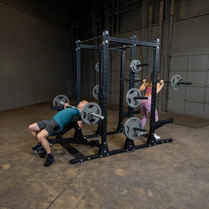 Two individuals exercising using the Body-Solid Pro ClubLine Commercial Double Half Rack Kit SPRDBLKIT in a gym setting.