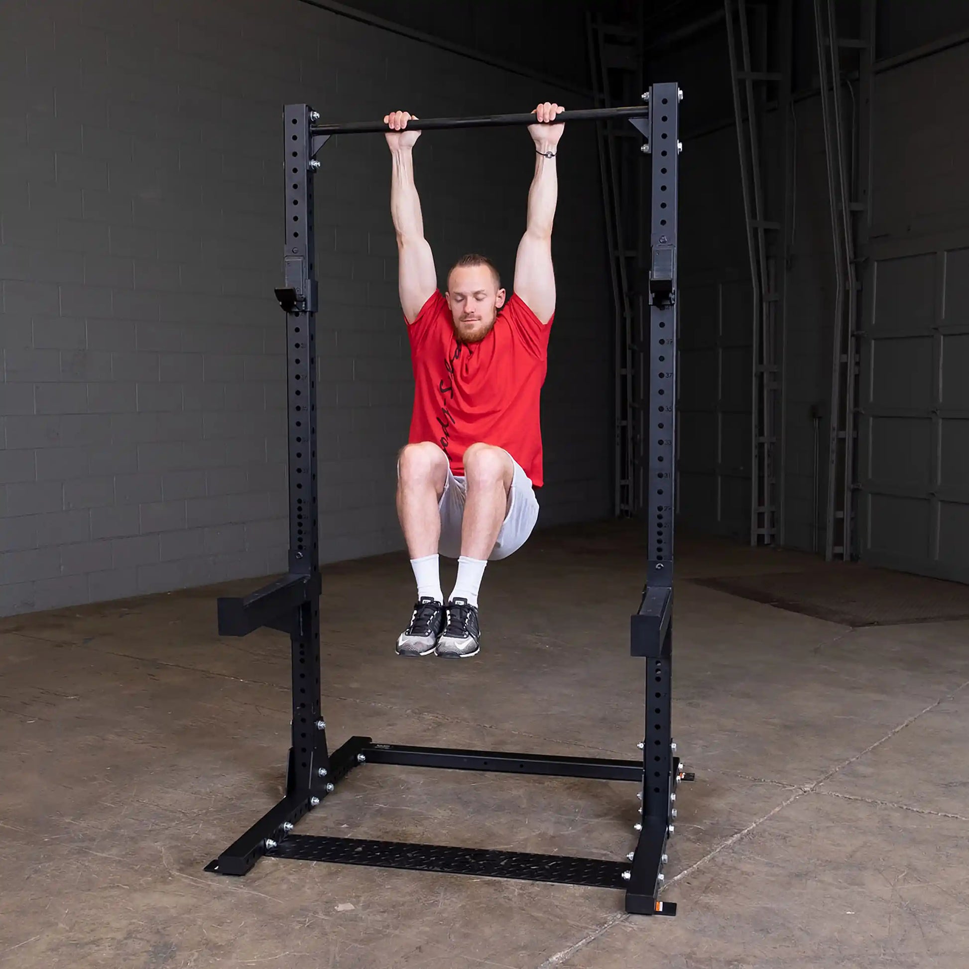Man performing a hanging leg raise on a Body-Solid Pro ClubLine Commercial Half Rack SPR500 in a gym setting.