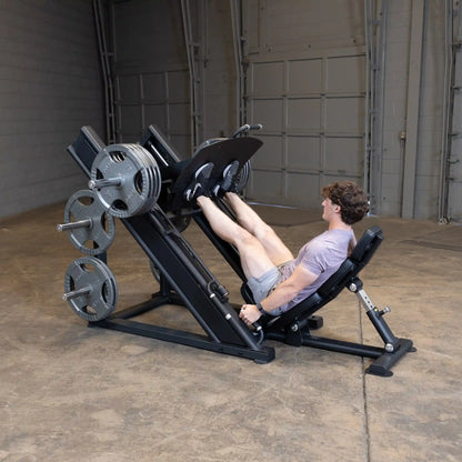 A person using the Body-Solid Pro ClubLine Commercial Leg Press Machine SGLP500 in a gym setting, performing leg press exercises with weights.