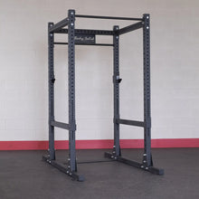 Body-Solid Pro ClubLine Commercial Power Rack SPR1000 in a gym setting against a light-colored brick wall.