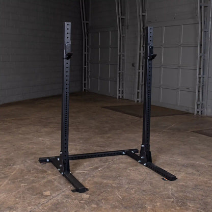 Body-Solid Pro ClubLine Commercial Squat Stand SPR250 standing in a spacious industrial-style room with concrete floors and gray brick walls.