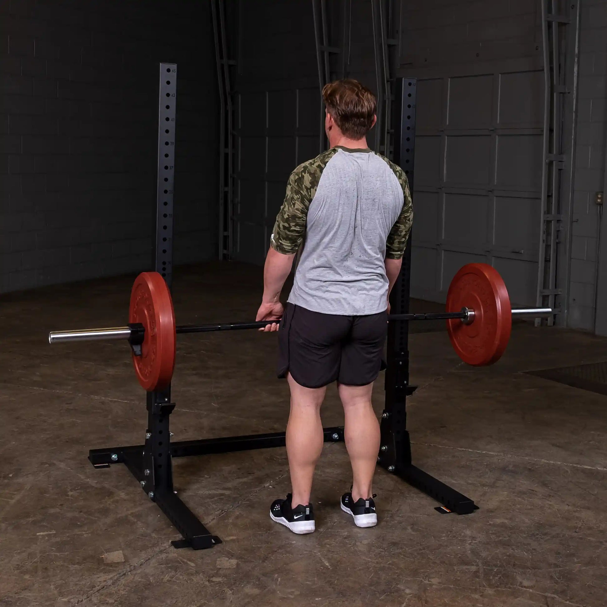 Man lifting weights on a Body-Solid Pro ClubLine Commercial Squat Stand SPR250 in a gym setting.