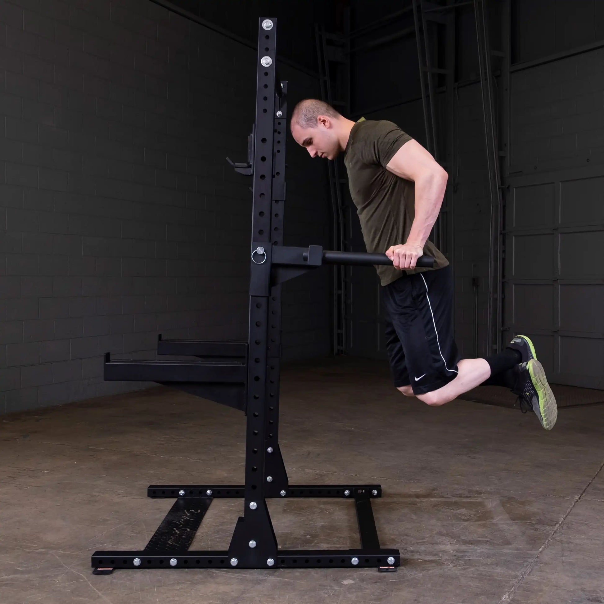 A person performing dips on the Body-Solid Pro ClubLine Dip Station Attachment SPRDIP in a gym setting.