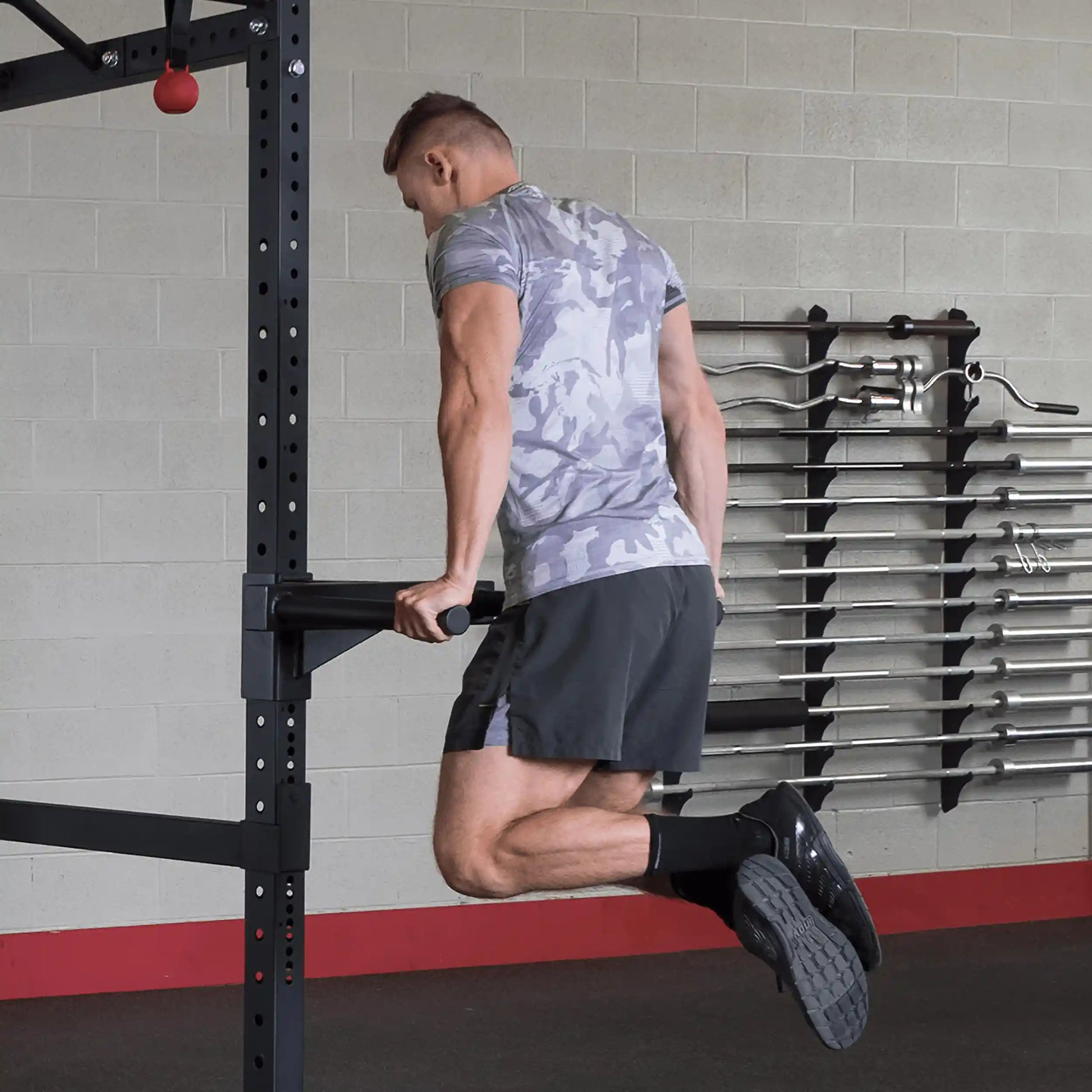 A person performing dips on the Body-Solid Pro ClubLine Dip Station Attachment SPRDIP in a gym setting, showcasing strength training.