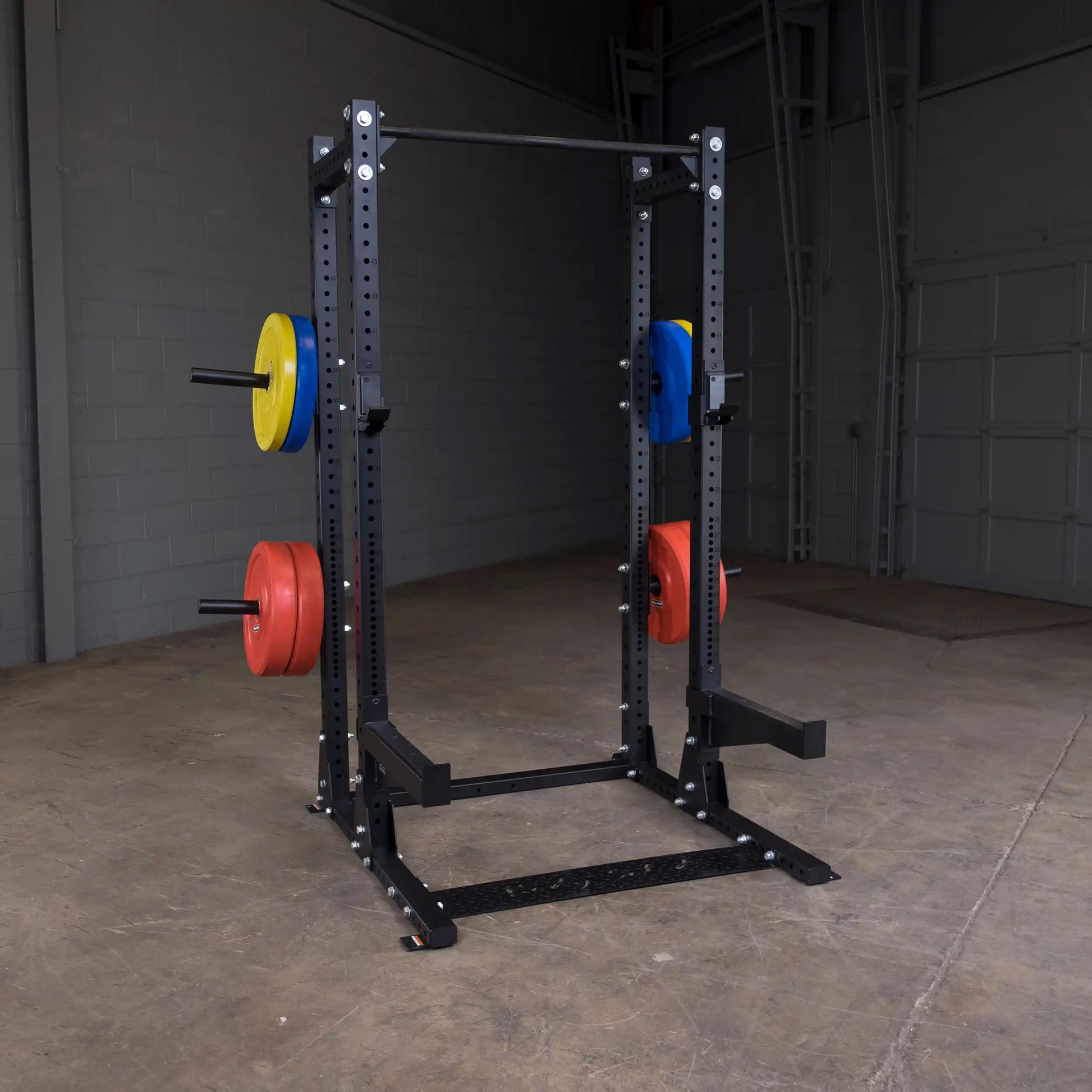 Body-Solid Pro ClubLine Extended Commercial Half Rack SPR500BACK with colorful weight plates attached, in a large warehouse gym setting.