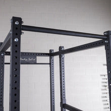 Close-up of a Body-Solid power rack, featuring a sturdy black frame with adjustable height settings and a horizontal bar, set against a light-colored wall.