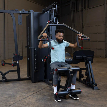 A person using the Body-Solid Pro ClubLine Four-Stack Gym S1000, performing an exercise while seated in a fitness facility.