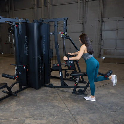 A woman using the Body-Solid Pro ClubLine Four-Stack Gym S1000 for a workout, demonstrating an exercise in a spacious gym environment.