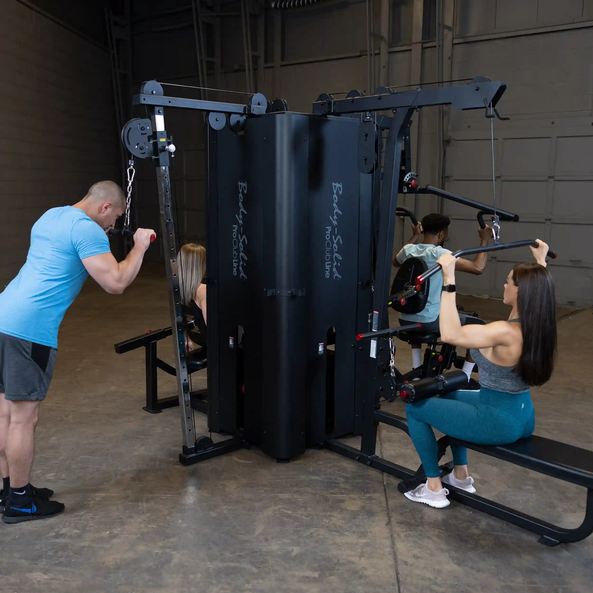 A fitness scene featuring the Body-Solid Pro ClubLine Four-Stack Gym S1000, with three individuals engaged in various workouts, showcasing strength training equipment in a spacious gym environment.