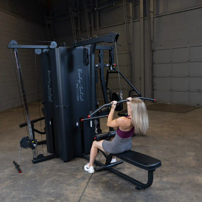 A person using the Body-Solid Pro ClubLine Four-Stack Gym S1000, performing a seated exercise with a bar attachment in a spacious gym environment.