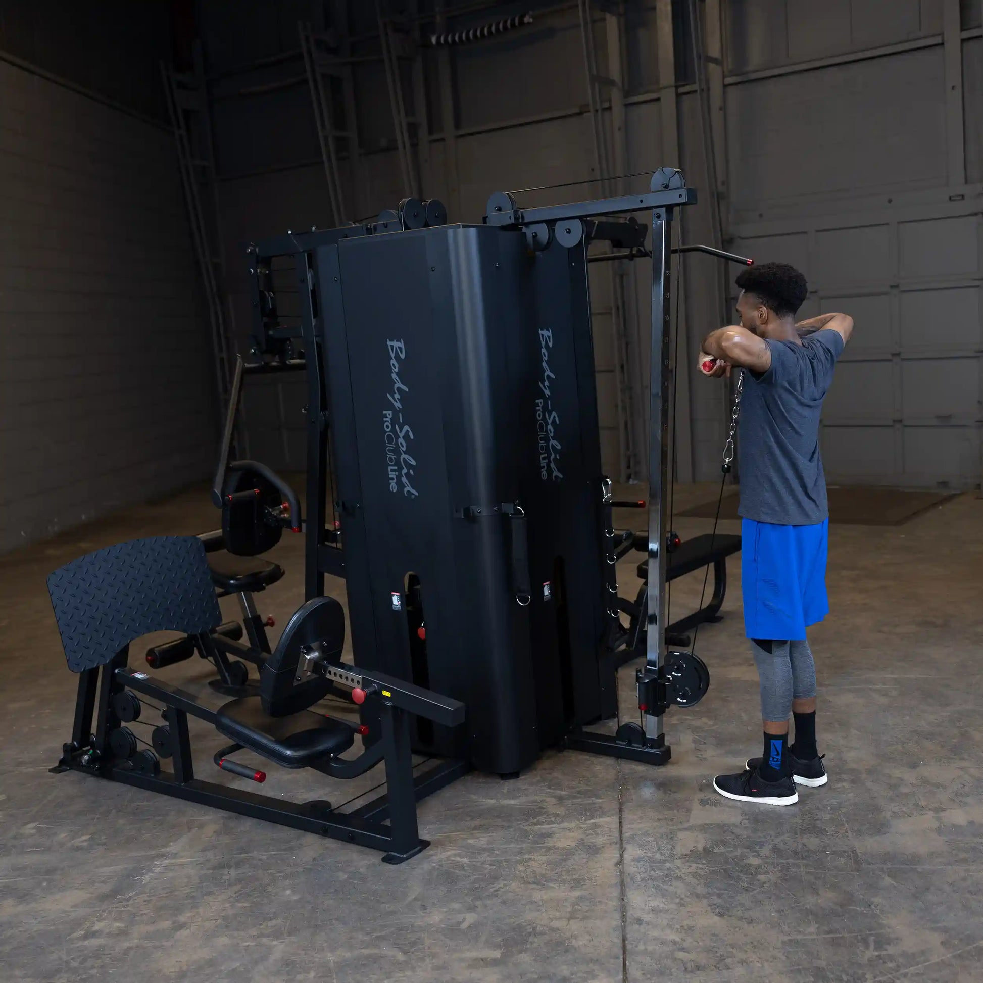 A person using the Body-Solid Pro ClubLine Four-Stack Gym S1000 in a spacious training area, performing an exercise with cables.
