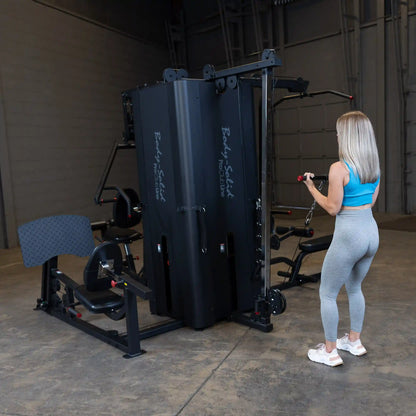 A woman using the Body-Solid Pro ClubLine Four-Stack Gym S1000, performing an exercise in a spacious gym environment.