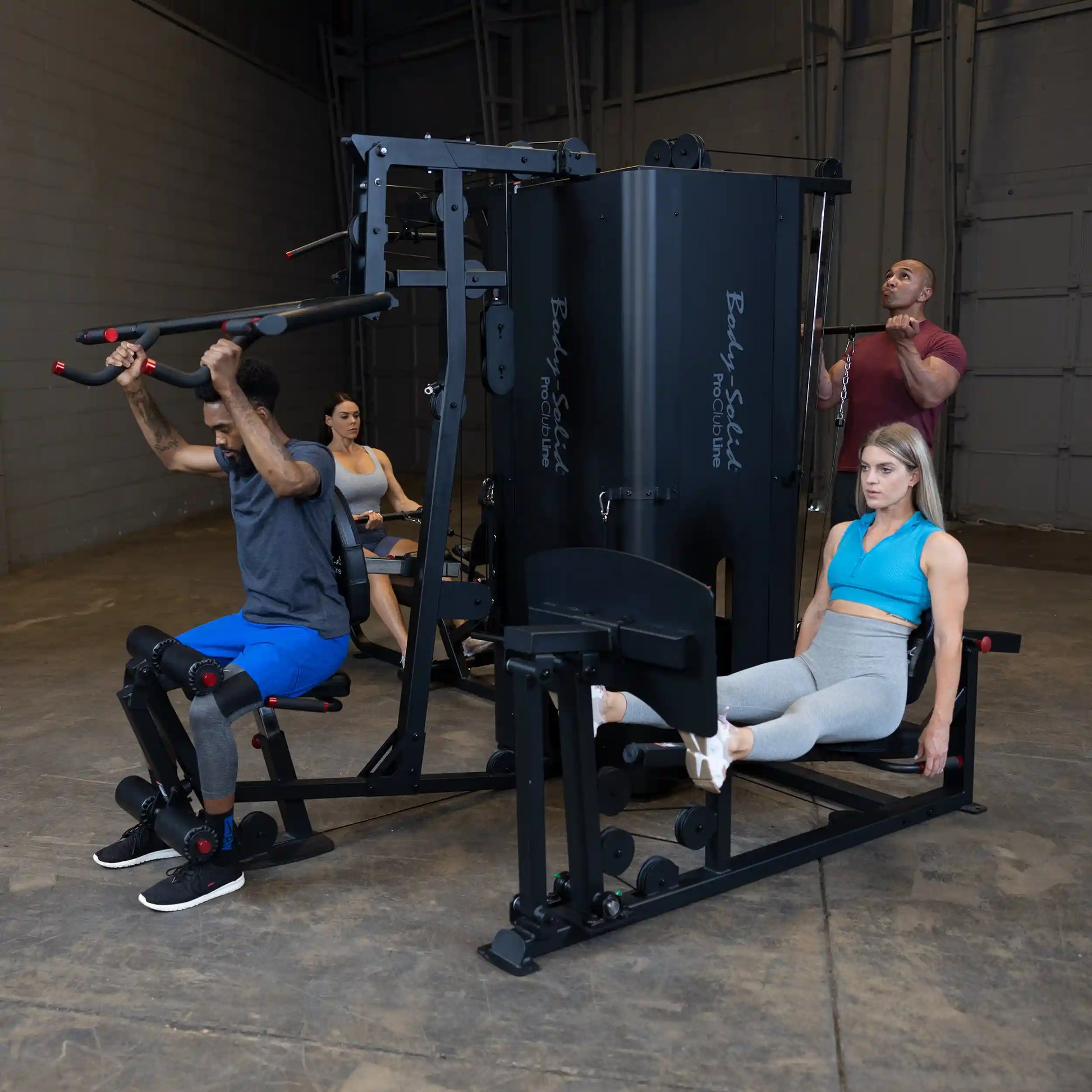 Four individuals using the Body-Solid Pro ClubLine Four-Stack Gym S1000 in a fitness studio, engaging in various strength training exercises.