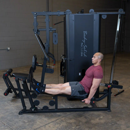 A man performing leg exercises on the Body-Solid Pro ClubLine Four-Stack Gym S1000, showcasing its various attachments and equipment in a gym setting.