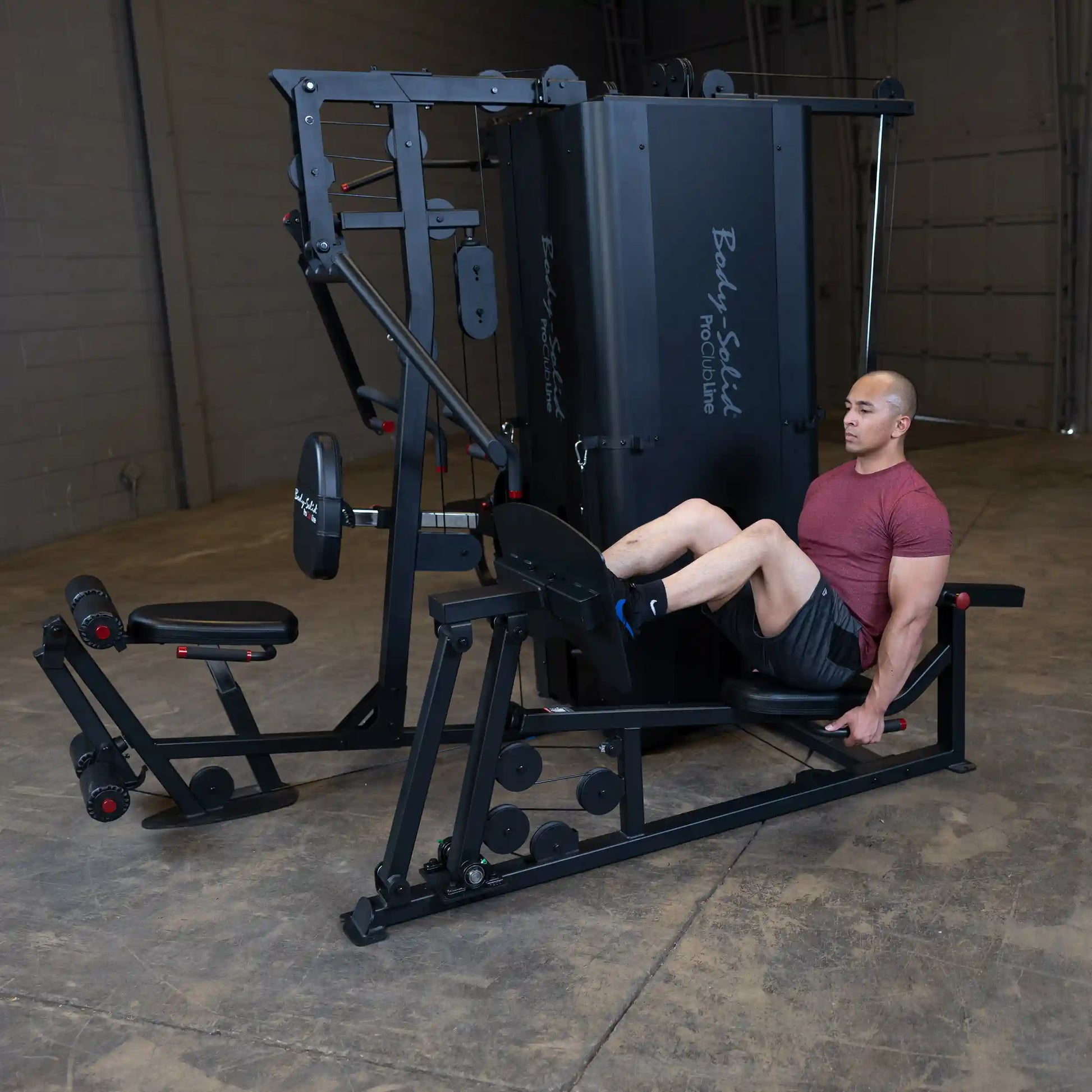 A man performing leg exercises on the Body-Solid Pro ClubLine Four-Stack Gym S1000, showcasing the gym equipment in a spacious indoor setting.