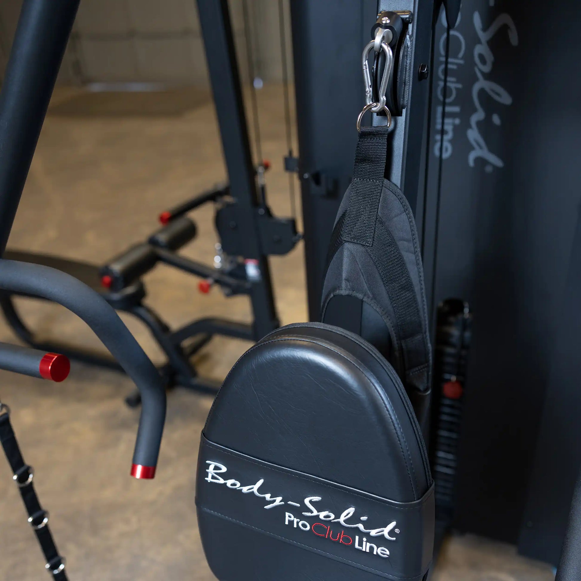 Close-up of the Body-Solid Pro ClubLine Four-Stack Gym S1000, featuring a padded handle attachment and part of the gym equipment structure in the background.