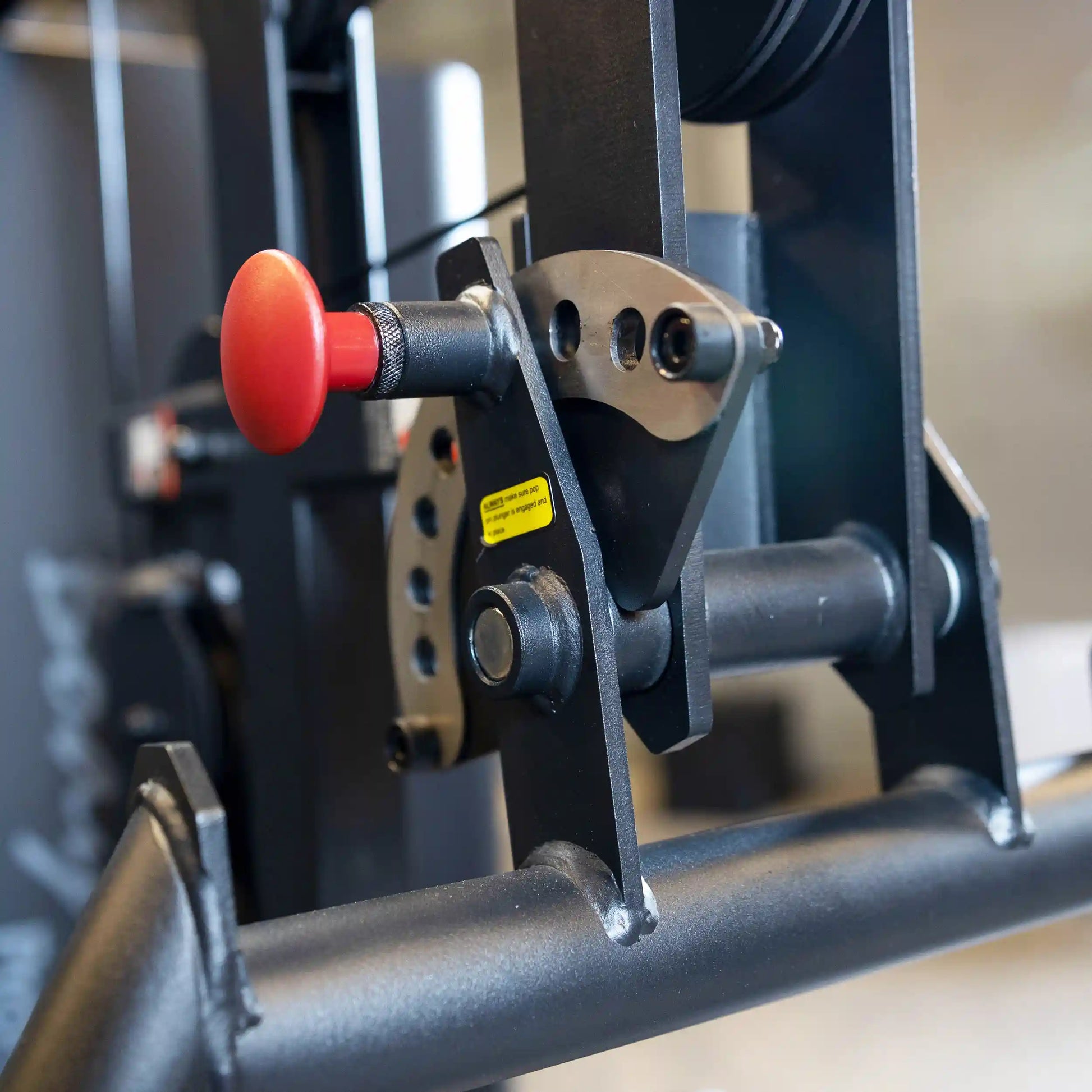 Close-up view of the adjustment mechanism on the Body-Solid Pro ClubLine Four-Stack Gym S1000, featuring a red adjustment knob and metal components.