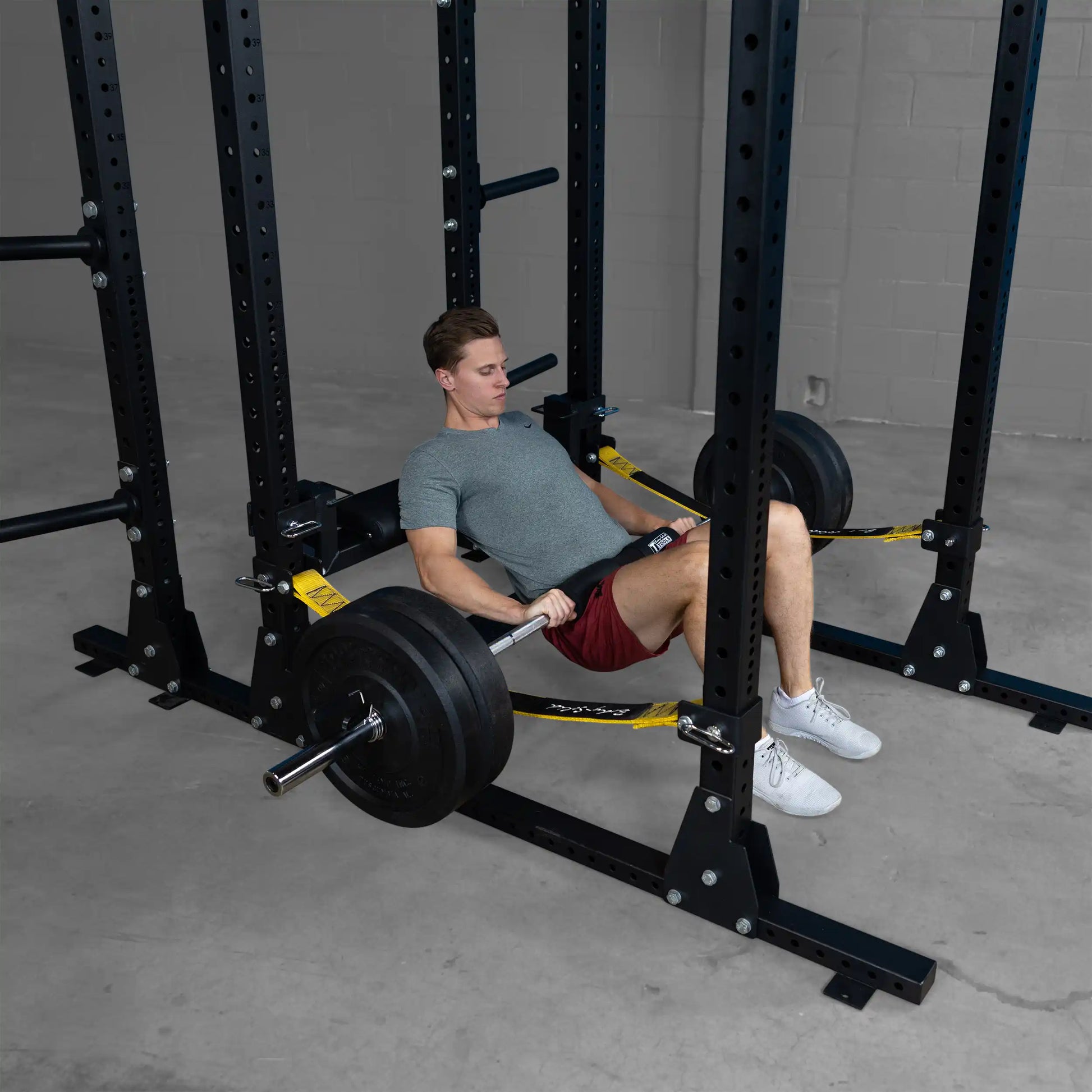 A person using the Body-Solid Pro ClubLine Hip Thrust Attachment SPRHT in a gym setting, performing hip thrusts with a weighted barbell.