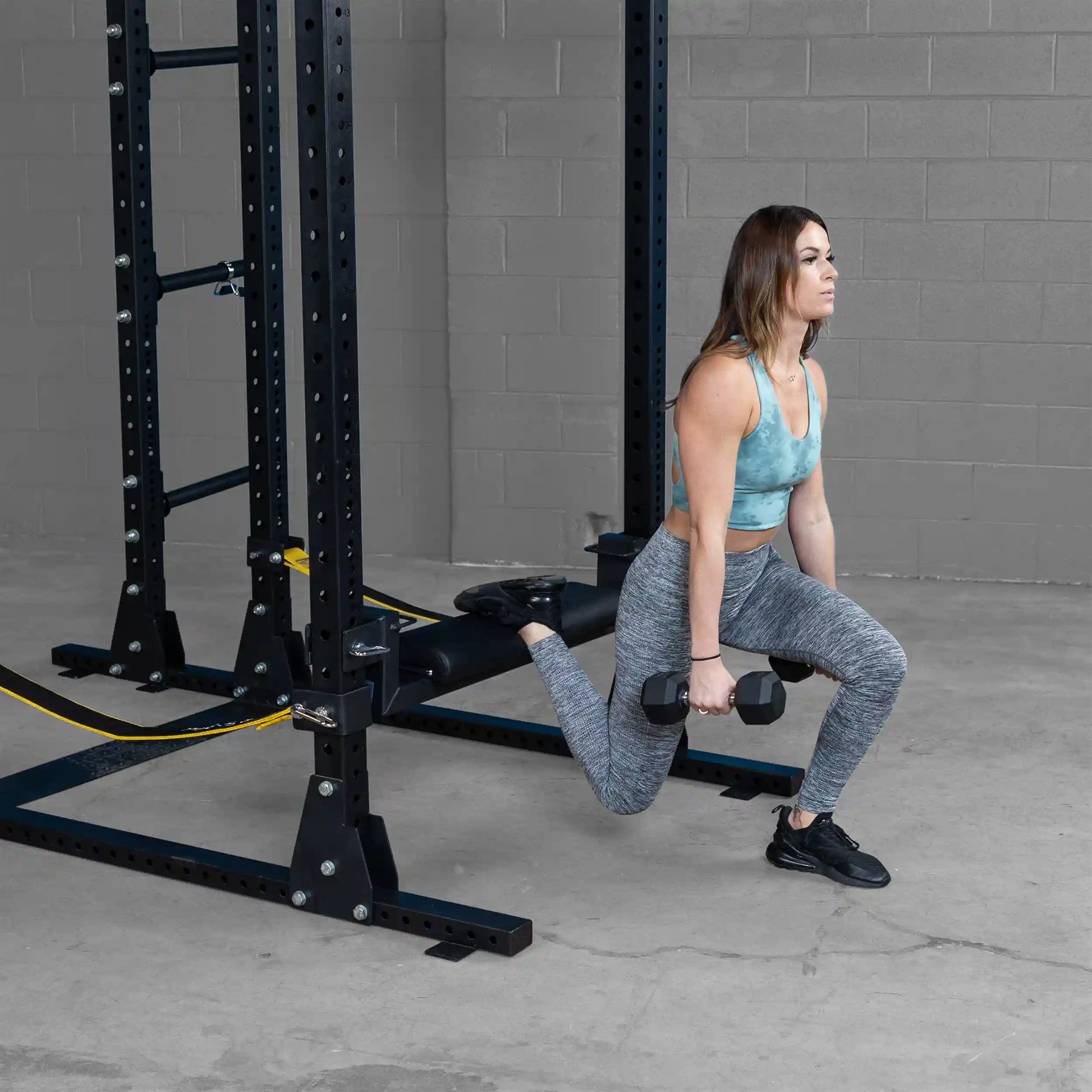 Person performing an exercise using the Body-Solid Pro ClubLine Hip Thrust Attachment SPRHT, demonstrating proper form with dumbbells in a gym setting.