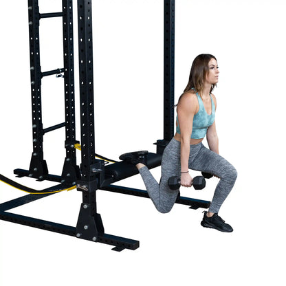Woman performing a hip thrust exercise using the Body-Solid Pro ClubLine Hip Thrust Attachment SPRHT, holding dumbbells while positioned on a gym equipment setup.