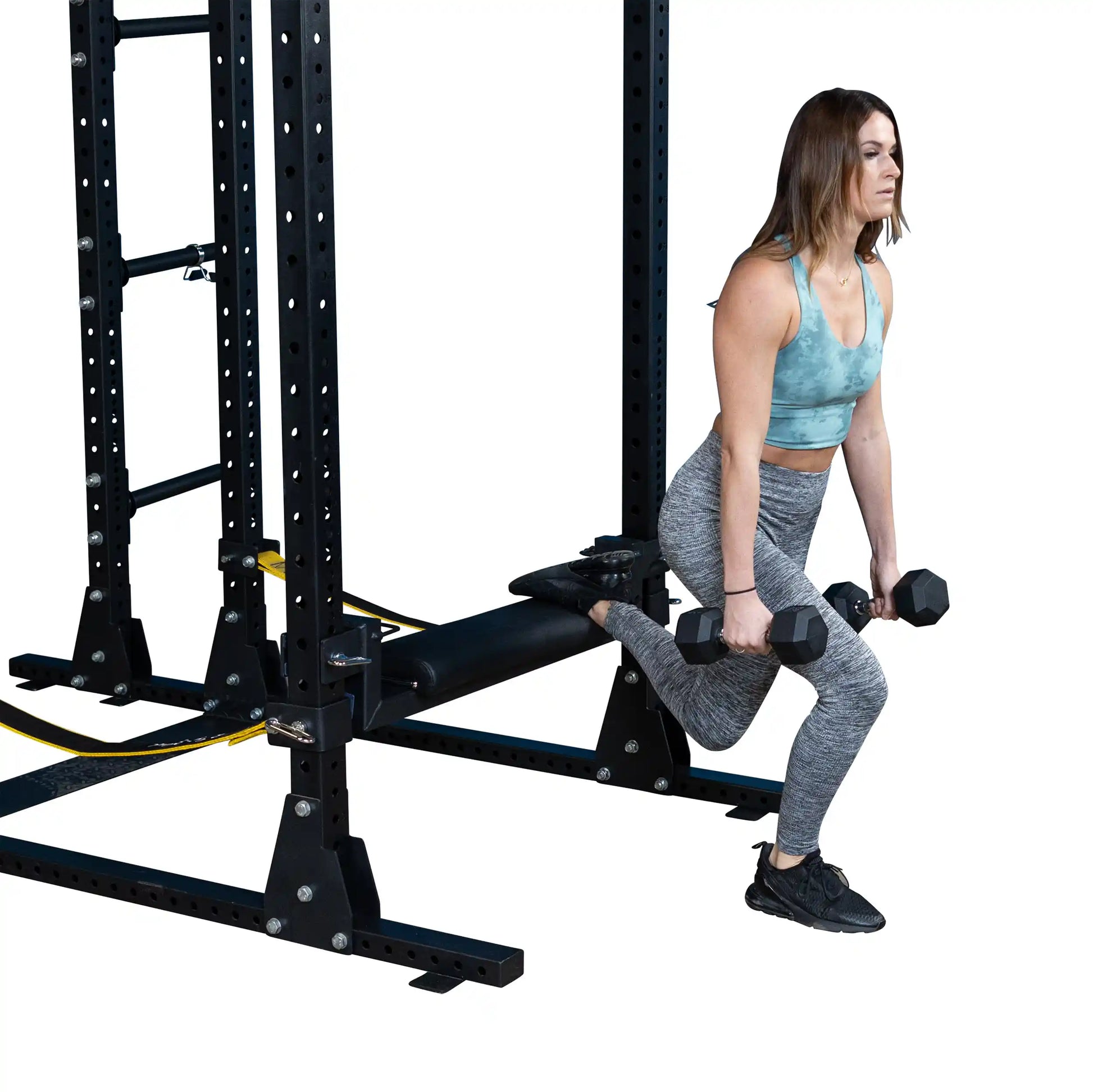A woman performing a single-leg hip thrust using the Body-Solid Pro ClubLine Hip Thrust Attachment SPRHT, with dumbbells in hand, in a gym setting.