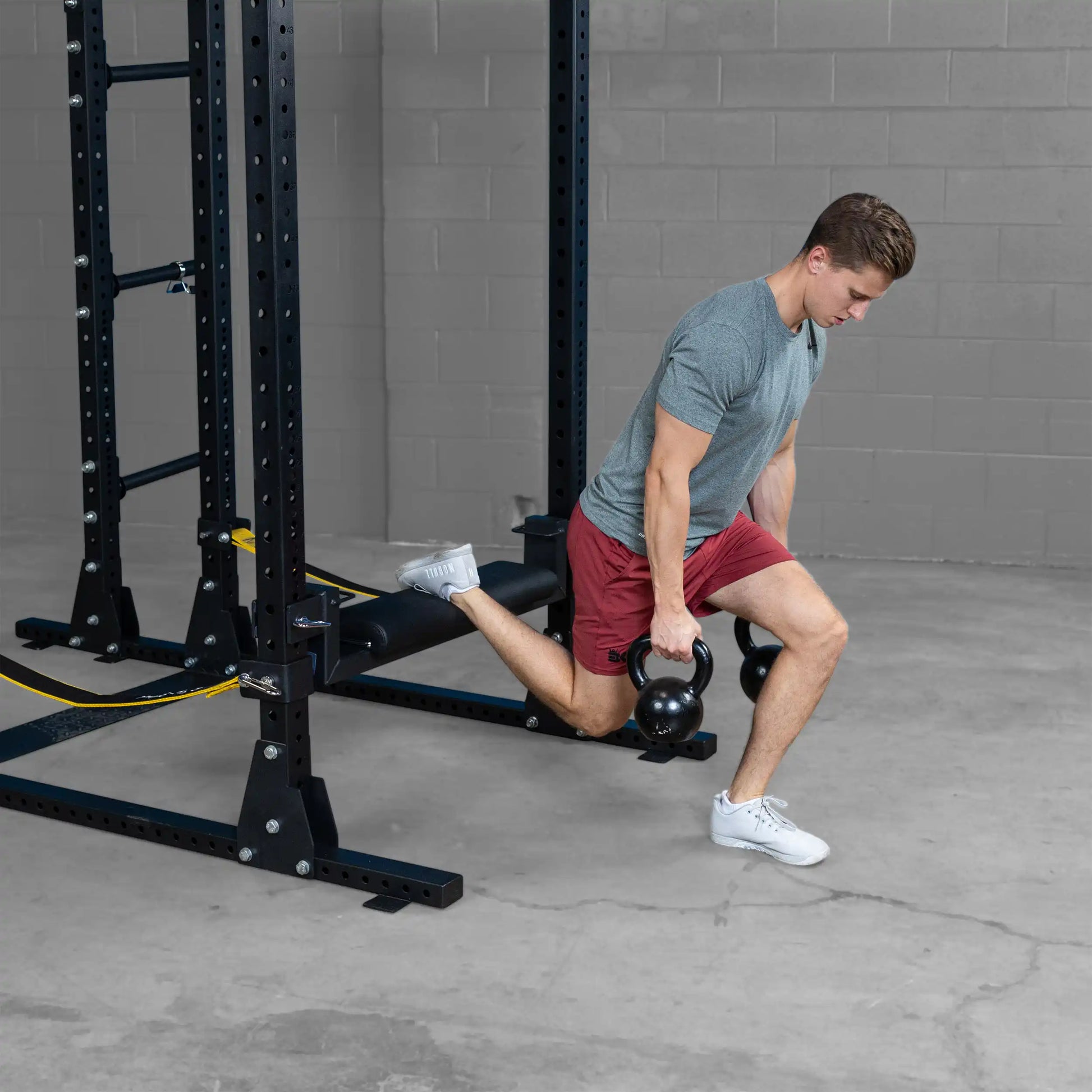 A person performing an exercise with kettlebells using the Body-Solid Pro ClubLine Hip Thrust Attachment SPRHT, demonstrating proper form in a gym setting.