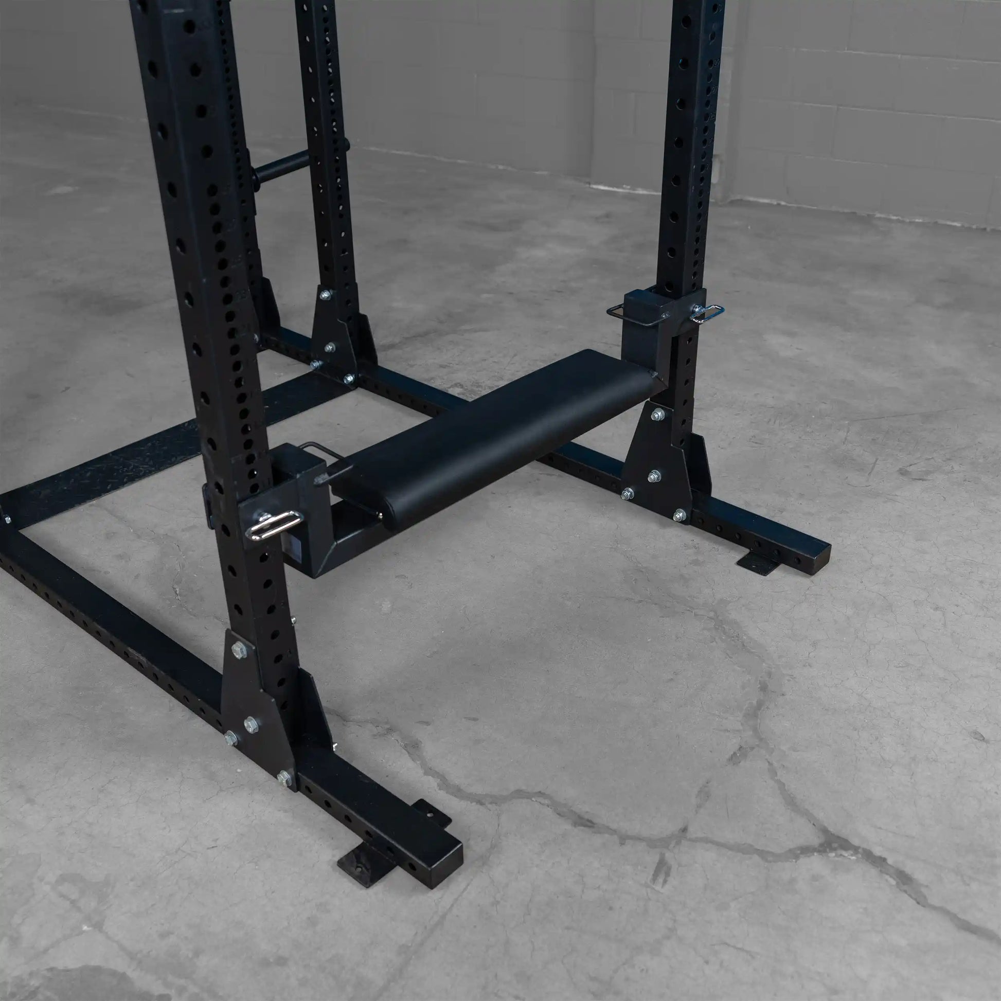 Close-up of the Body-Solid Pro ClubLine Hip Thrust Attachment SPRHT, featuring a padded roller and sturdy black metal construction mounted on a weight rack.