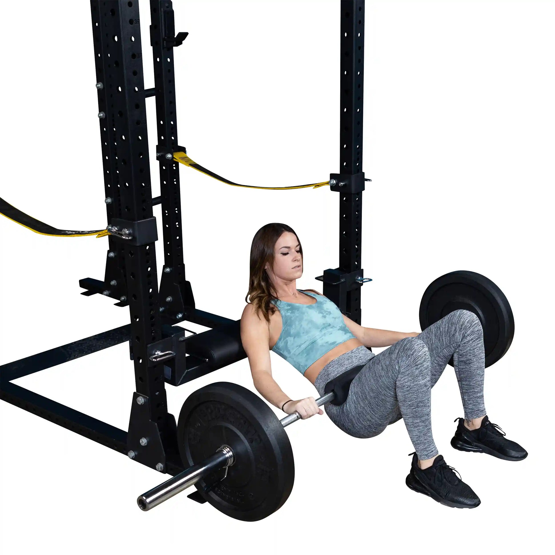 A woman demonstrating the Body-Solid Pro ClubLine Hip Thrust Attachment SPRHT, performing a hip thrust exercise with a barbell in a gym setting.