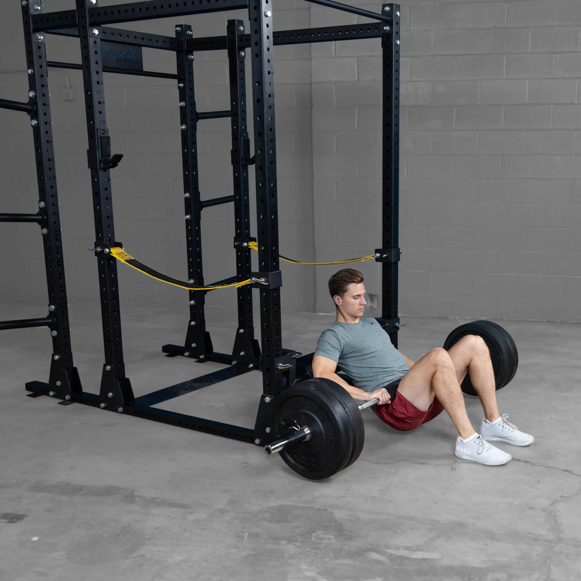 Man performing hip thrust exercise using the Body-Solid Pro ClubLine Hip Thrust Attachment SPRHT, with a barbell and weights in a gym setting.
