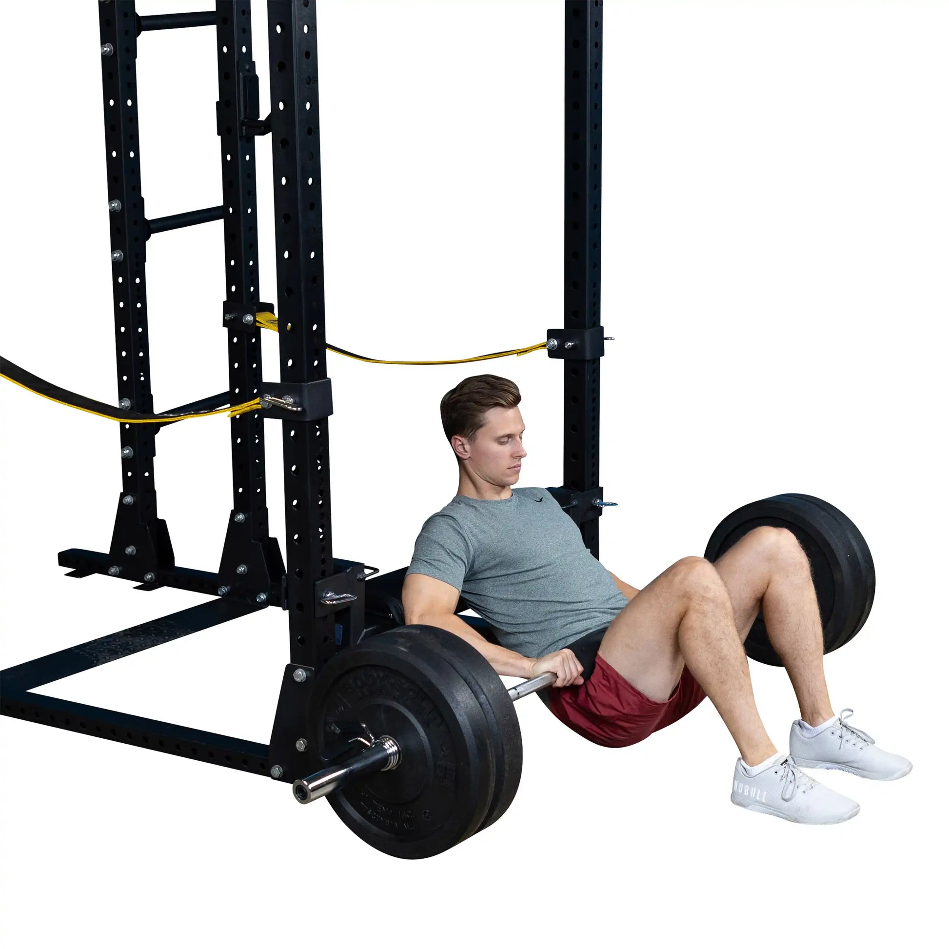 A man performing hip thrusts using the Body-Solid Pro ClubLine Hip Thrust Attachment SPRHT, seated with a barbell, in a gym setting.