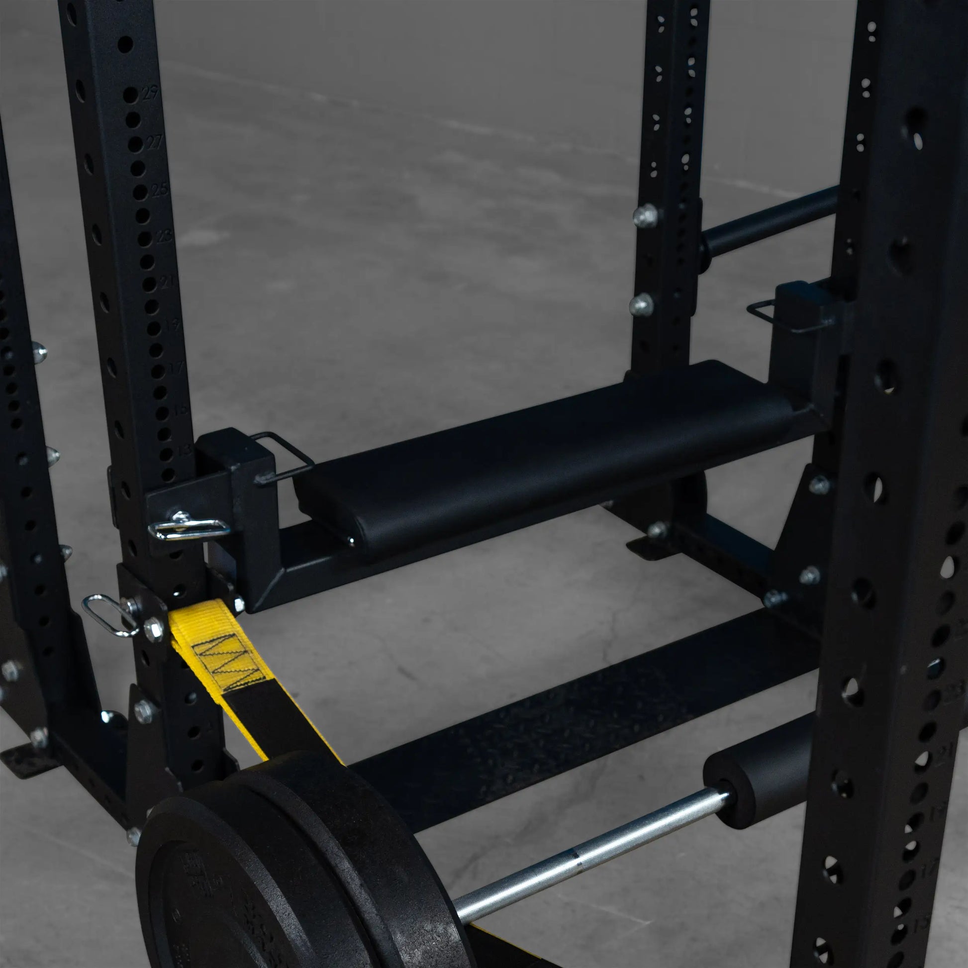 Close-up view of the Body-Solid Pro ClubLine Hip Thrust Attachment SPRHT, featuring a padded surface and attachment points for a barbell within a squat rack setup.