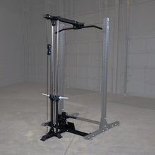 Body-Solid Pro ClubLine Lat Attachment SPRHLA mounted on a gym frame, featuring a pull-down bar and cable system, set in a spacious, empty gym environment.
