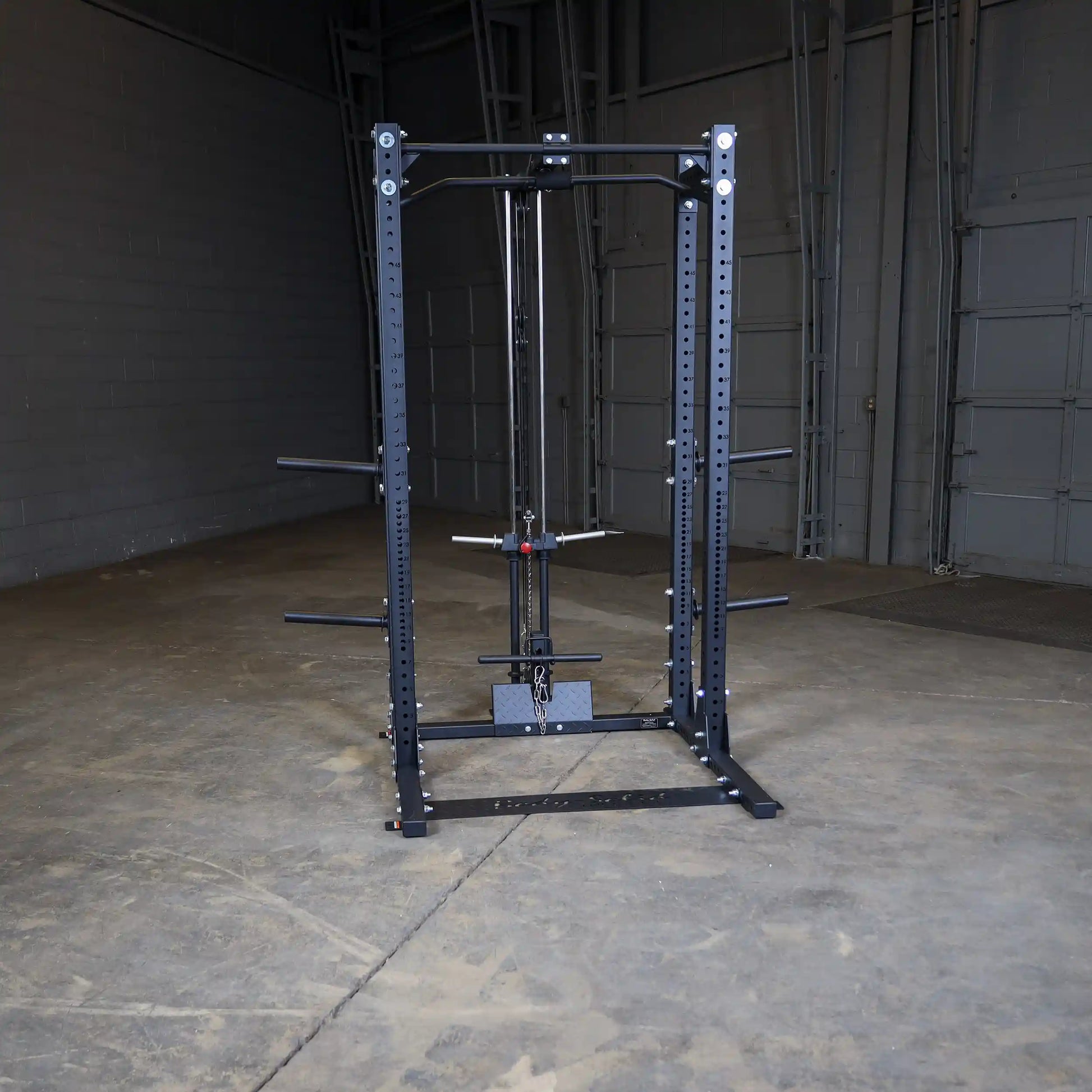 A Body-Solid Pro ClubLine Lat Attachment SPRHLA positioned in an empty gym space, showcasing its sleek black design and functional features for strength training.