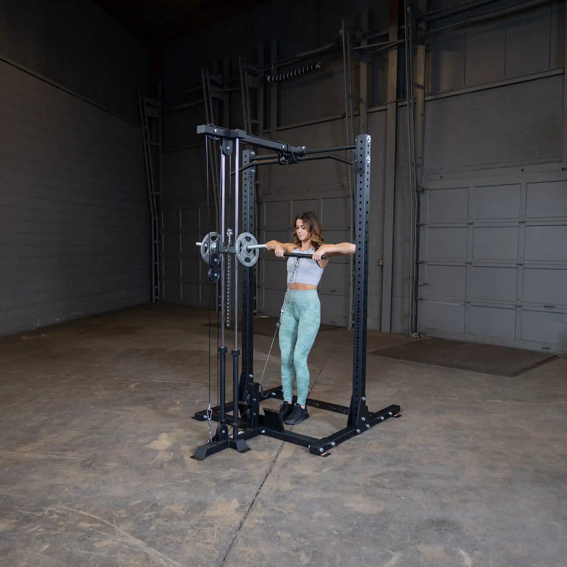 A woman performing a workout using the Body-Solid Pro ClubLine Lat Attachment SPRHLA in a spacious gym setting.