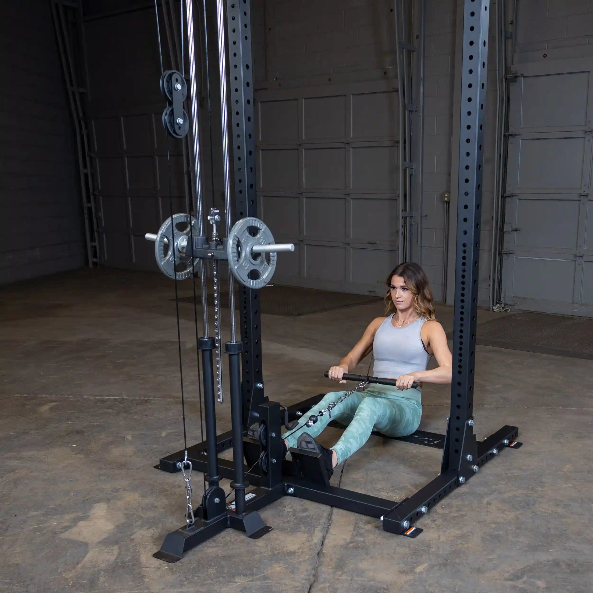 A woman using the Body-Solid Pro ClubLine Lat Attachment SPRHLA for a seated row exercise in a gym setting.