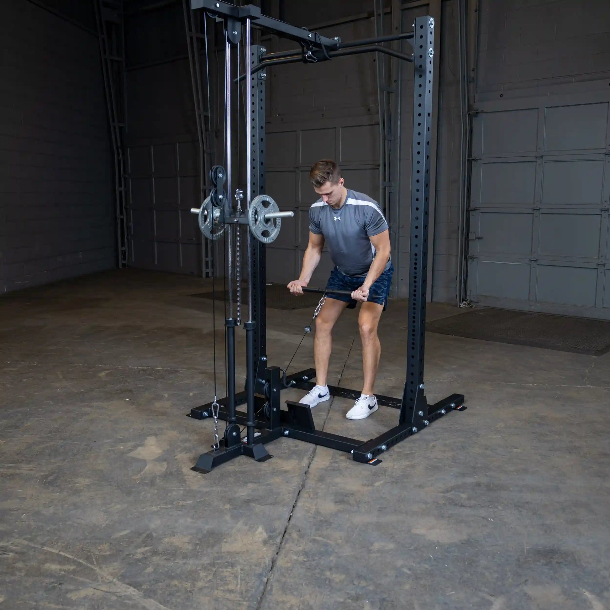 A person using the Body-Solid Pro ClubLine Lat Attachment SPRHLA for a workout, performing a lat pull-down exercise in a spacious gym environment.