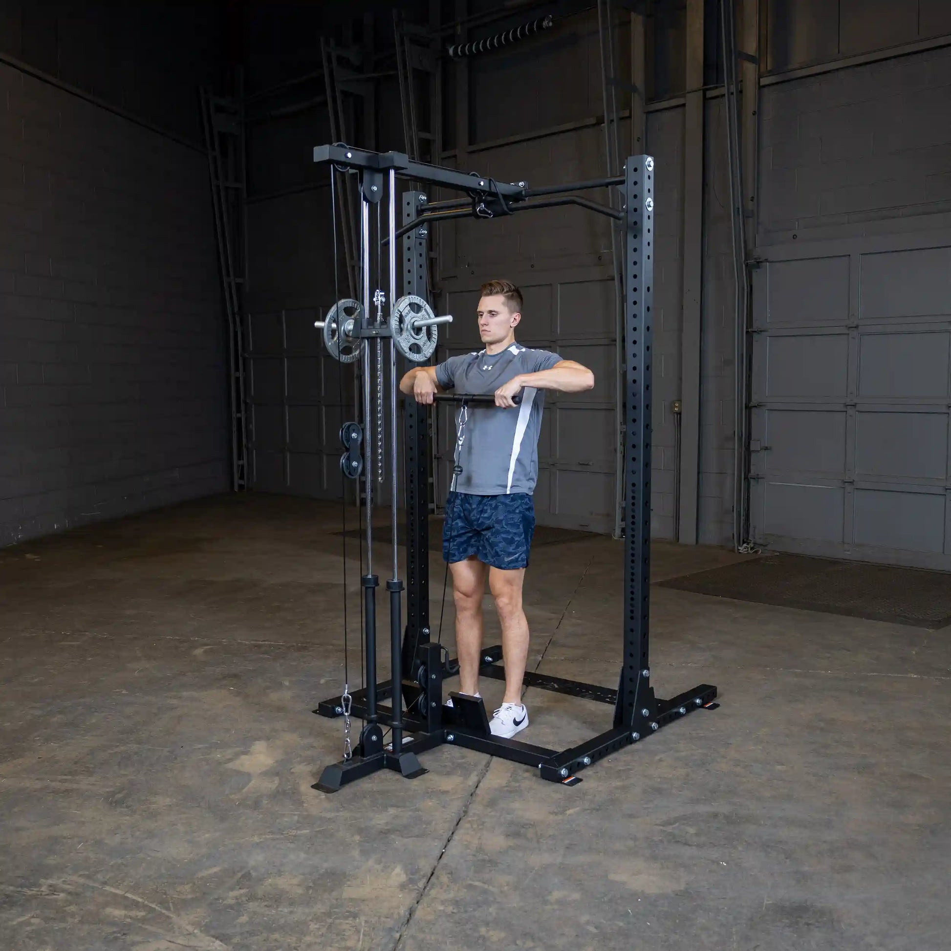 A person using the Body-Solid Pro ClubLine Lat Attachment SPRHLA in a gym setting, performing a lat pulldown exercise with weights attached to the machine.