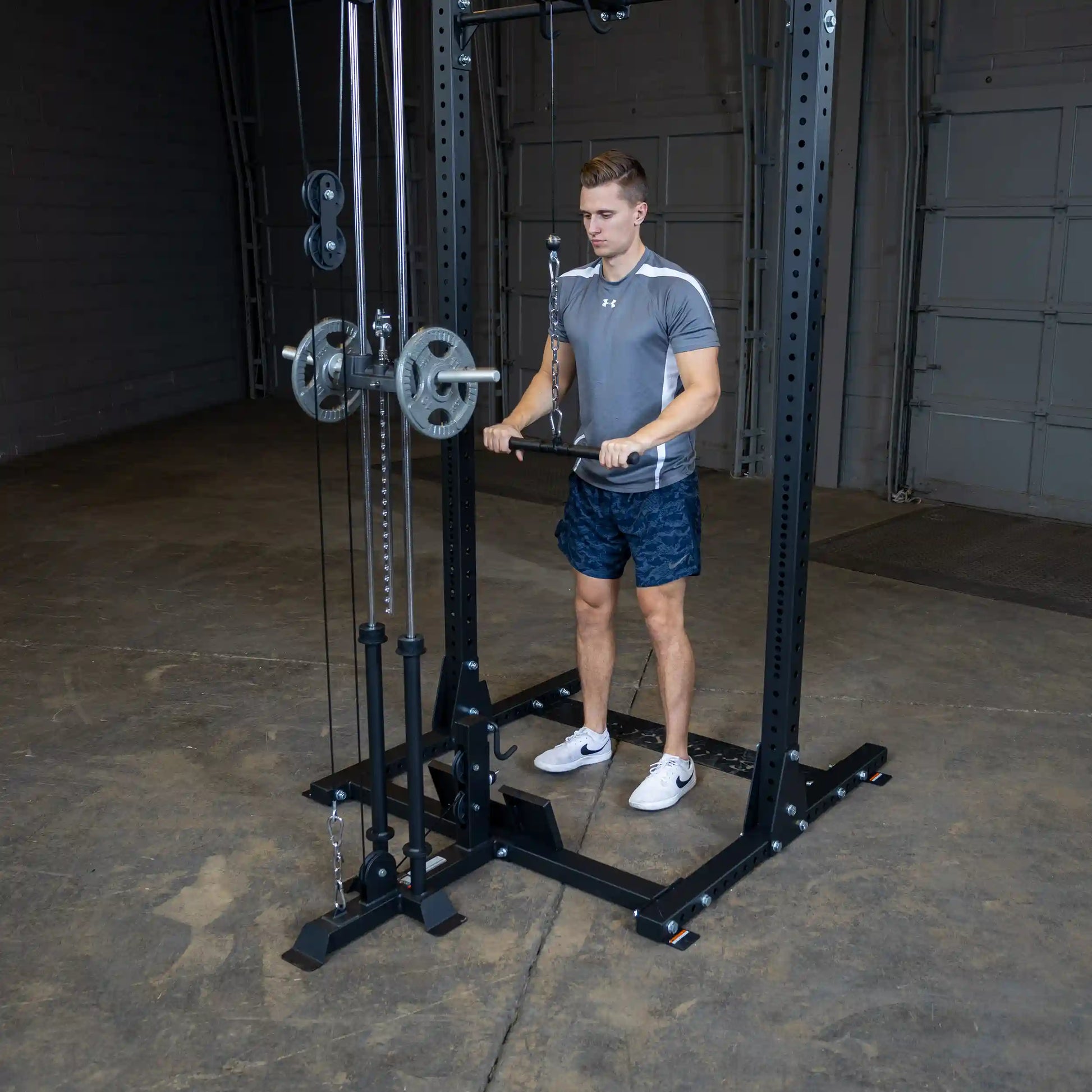 A man using the Body-Solid Pro ClubLine Lat Attachment SPRHLA in a gym setting, performing an exercise with weights on a cable machine.
